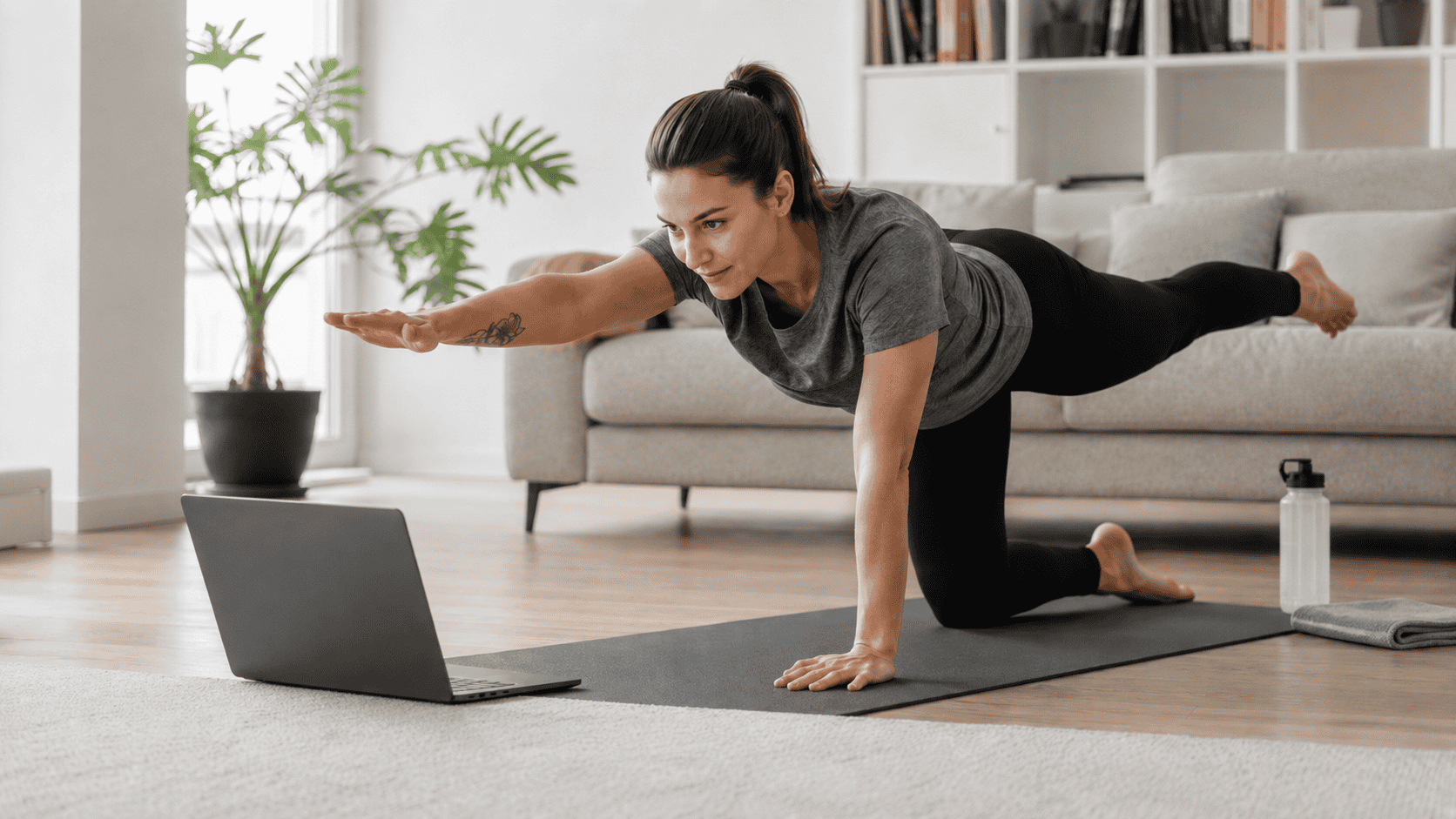 Eine Person trainiert zu Hause vor einem Laptop und folgt einer Online-Trainingseinheit.